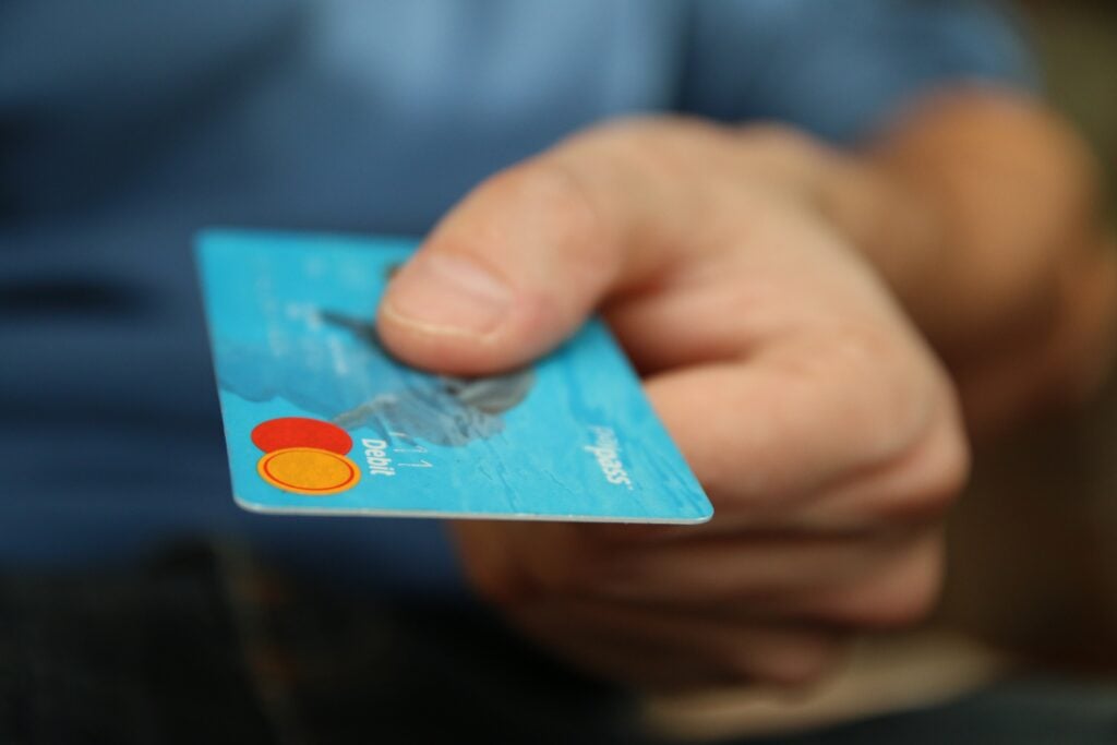A picture of a person holding out a credit card