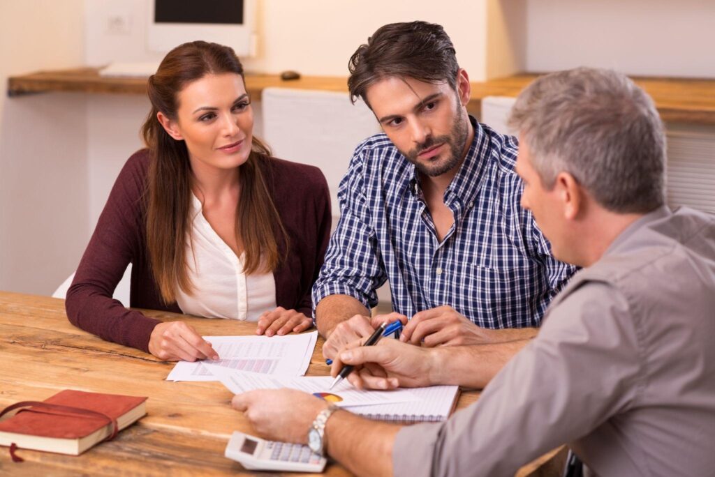 A businessman explains a loan policy to a young couple.