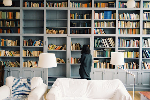 A lady standing in front of her home library.